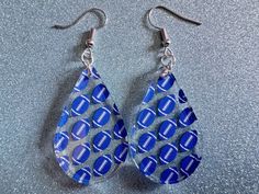 a pair of blue and white earrings with footballs on them sitting on a table