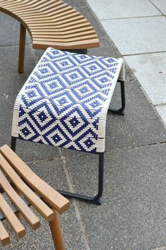 two wooden benches sitting next to each other on top of a cement floor covered in blue and white patterned fabric