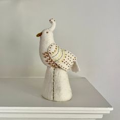 a white stuffed bird sitting on top of a shelf