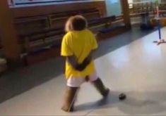 a young boy in yellow shirt and white shorts playing with a soccer ball on the floor