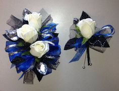 two white roses with blue and silver ribbons are on the wall next to each other