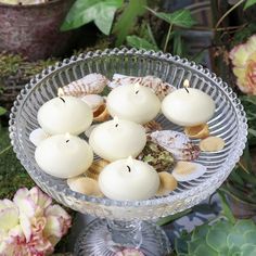 some candles are sitting in a glass bowl