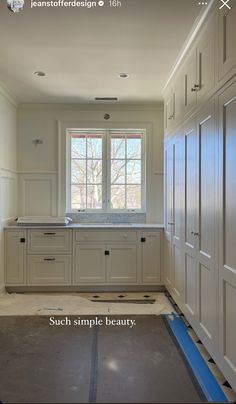 an empty kitchen with white cabinets and blue tape on the floor in front of it