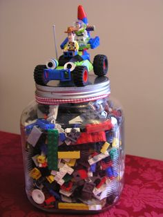 a jar filled with lots of legos on top of a red tablecloth covered table