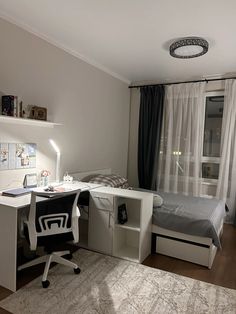 a bedroom with a bed, desk and chair next to a window in the room