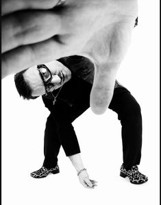 a man in black pants and leopard print shoes is pointing his finger at the camera