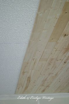 wood planks on the ceiling in a room with white painted walls and flooring