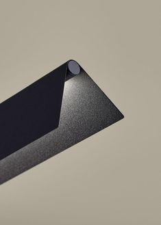 a close up of a black object on a gray background with the light reflecting off it