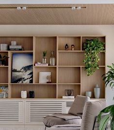 a living room filled with lots of furniture and plants on top of wooden bookshelves