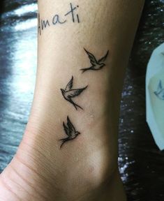 a tattoo on the foot of a woman with three birds flying above her feet that says amati