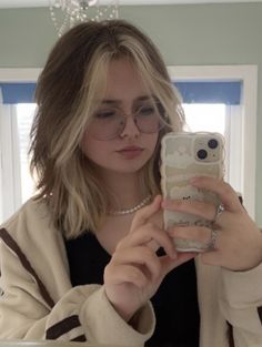 a woman taking a selfie in front of a mirror with her cell phone up to her ear