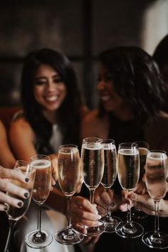 a group of women toasting with champagne glasses in front of them on a table