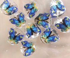 six blue butterflies sitting on top of each other in clear plastic wrappers with yellow and green designs