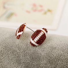 a pair of football shaped earrings sitting on top of a pillow next to a wall