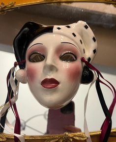 a white mask with red ribbon around it's neck and head in front of a mirror