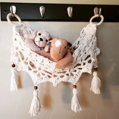 two teddy bears are sitting in a crocheted hammock with tassels