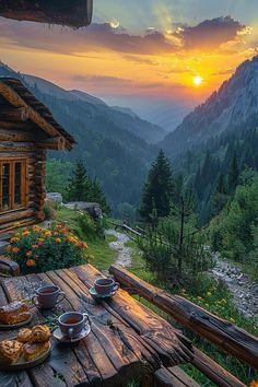 a wooden table topped with food on top of a lush green hillside covered in forest