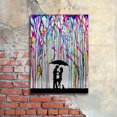 a couple holding an umbrella standing in front of a wall with paint splatters on it