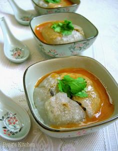 three bowls filled with soup and garnished with parsley on the tablecloth