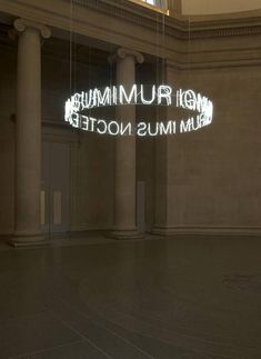 an empty room with columns and a neon sign that reads museum imus nocte