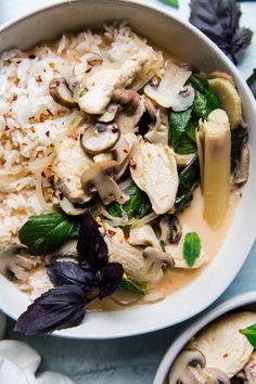 two bowls filled with rice, mushrooms and spinach on top of a blue table