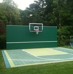 a basketball court in the middle of a grassy area with trees and bushes behind it