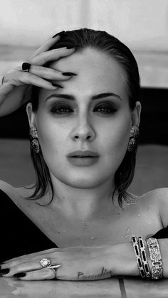 a black and white photo of a woman with her hands on her head, looking at the camera