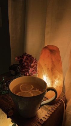 a cup of tea sitting on top of a wooden table next to a himalayan lamp