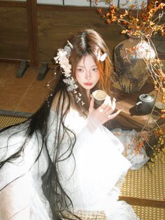 a woman in white dress sitting on floor next to vase