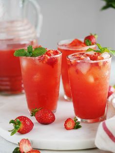 three glasses filled with watermelon and strawberries sitting on a white platter