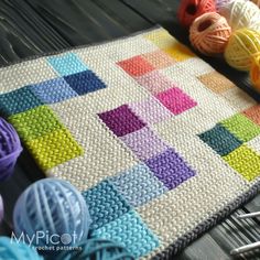 a crocheted blanket with balls of yarn on it