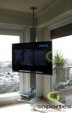 a flat screen tv mounted to the side of a wall in a living room next to a window