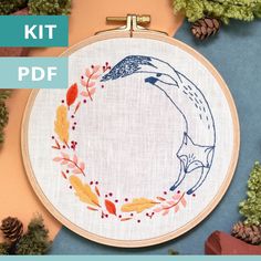 a hand embroidered hoop with an image of a bird on it and leaves around the hoop