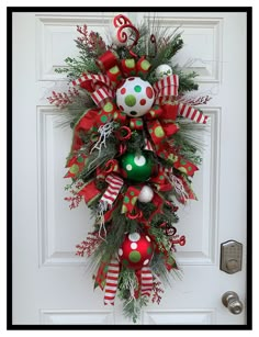 a red and green christmas wreath on the front door with ornaments hanging from it's sides