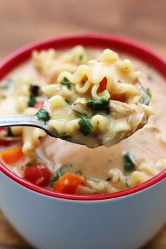 a spoon full of chicken noodle soup on a wooden table