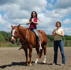 two women standing next to a brown horse