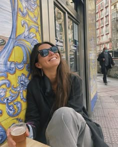 a woman sitting at a table with a beer in her hand and smiling for the camera