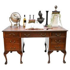 an antique desk with two drawers and a globe on top, surrounded by other items