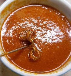 a bowl of tomato soup with a spoon in it