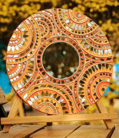 an orange and gold plate sitting on top of a wooden table next to a tree