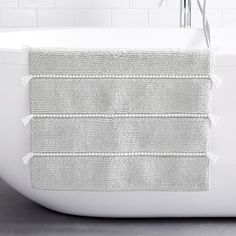 a white bath tub sitting next to a tiled wall