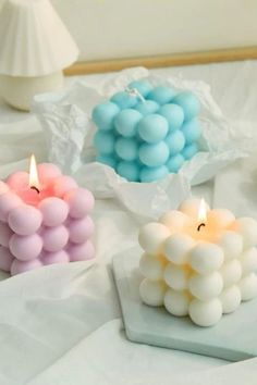 three candles are sitting on a table with white and blue balls in the middle of them