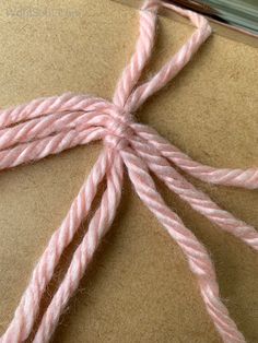 a piece of brown paper with pink yarn on it