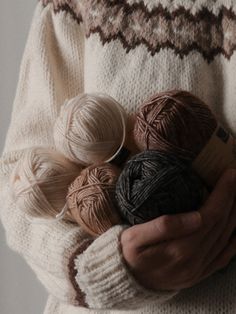 a person holding several balls of yarn in their hands while wearing knitted sweaters