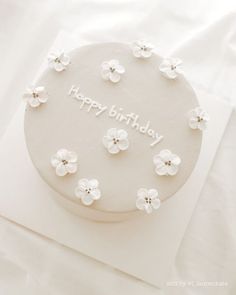 a birthday cake with white flowers on it and the words happy birthday written in frosting