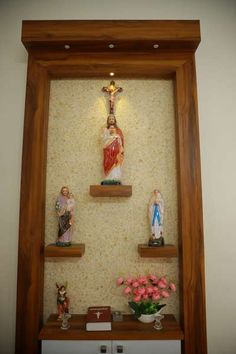 a shelf with some statues on top of it and flowers in front of the shelves