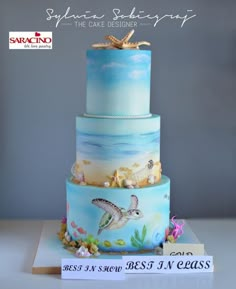 a three tiered cake decorated with sea animals and seashells is on display