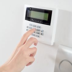 a person is pressing buttons on a wall mounted alarm control system with thermostaer