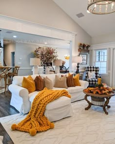 a living room filled with white furniture and lots of pillows on top of it's couches