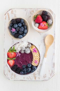 two bowls filled with fruit on top of a white tray